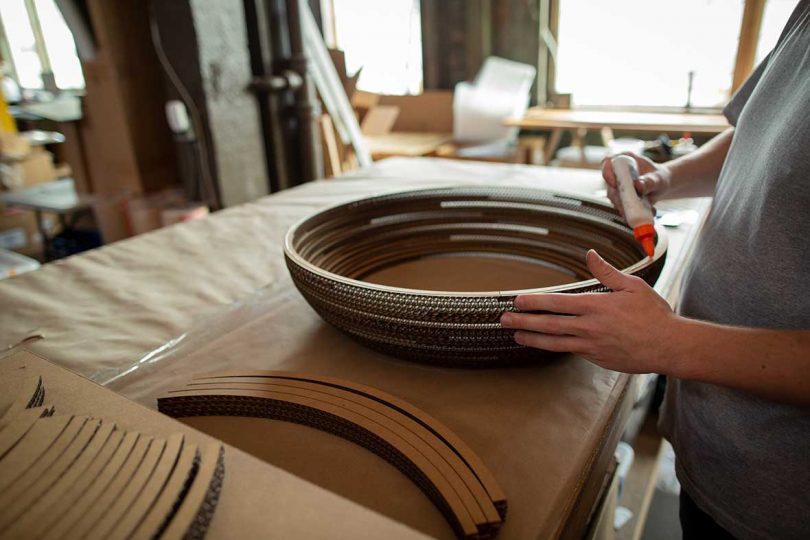 layers of cardboard bands are assembled by hand on work table