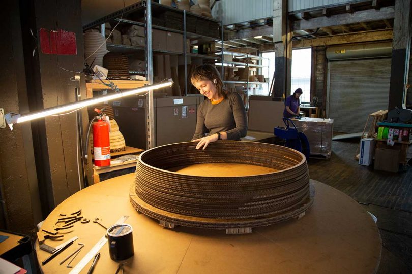 skilled worker hand assembles large circular light fixture