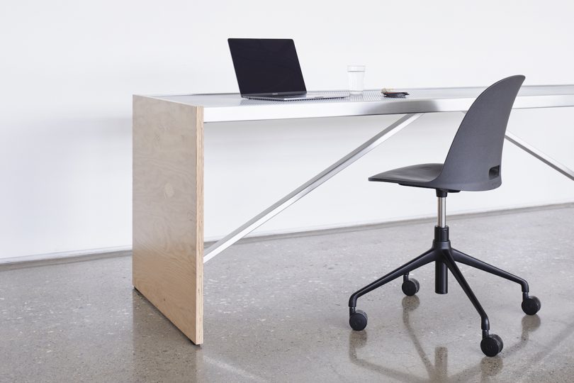 metal and wood table being used as desk with chair and laptop