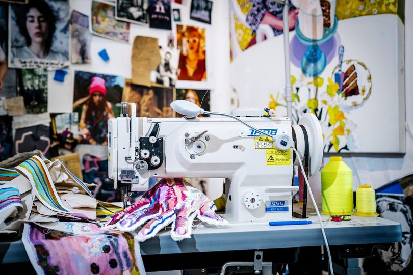 sewing machine on desk in front of a collaged wall