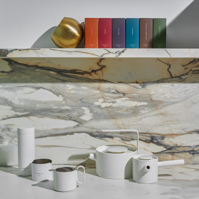 a library of colored tea boxes with white ceramic tea accessories on marble
