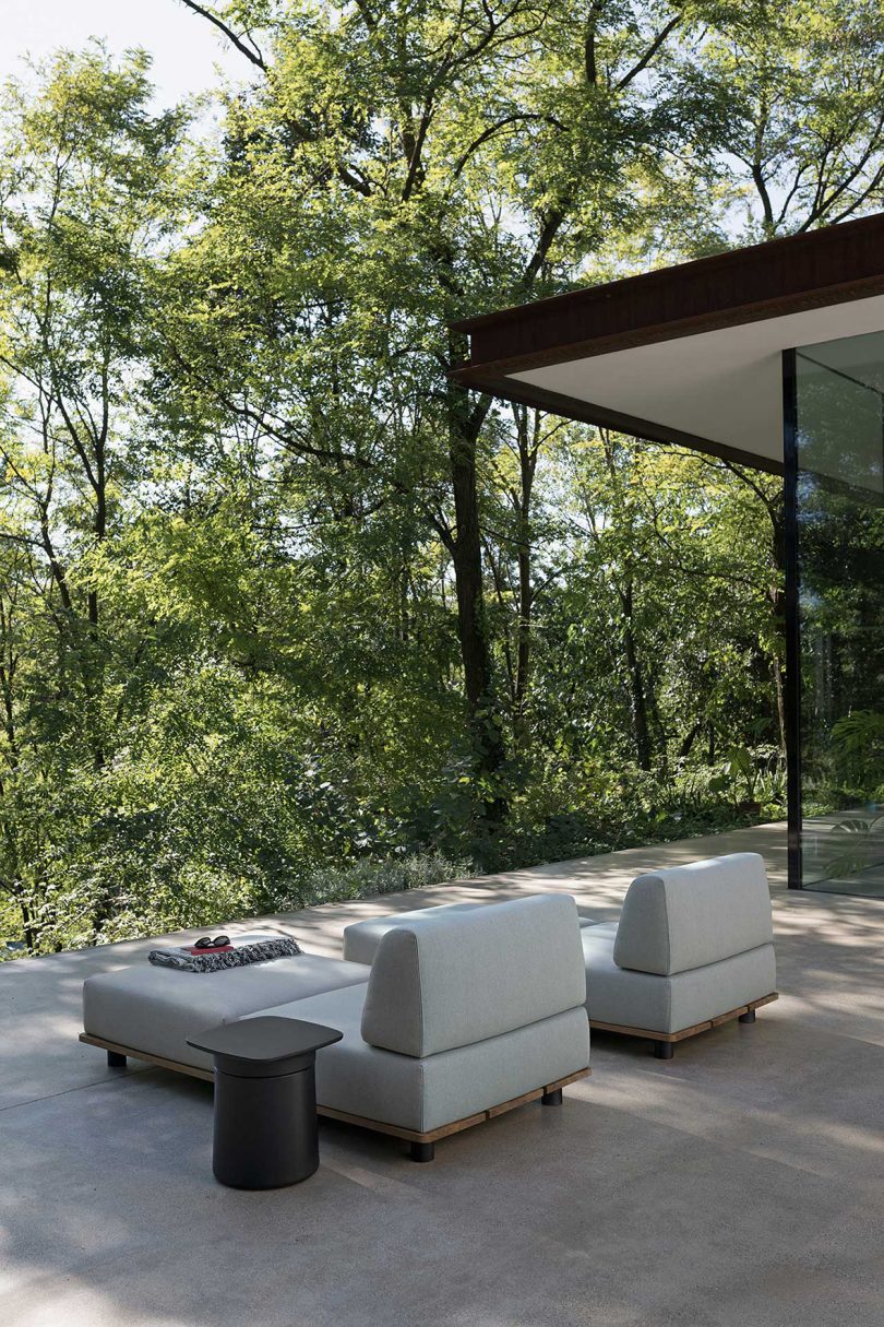 outdoor patio with two white loungers overlooking forest