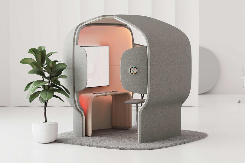 Flowspace Pod open felt lined cubicle with large screen computer illuminated with soft pink lighting.