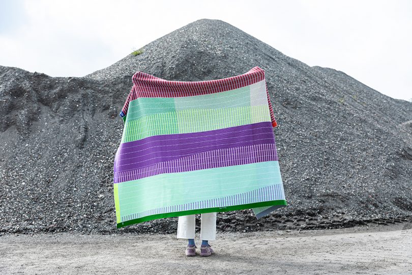 person holding blanket open in front of a mountain