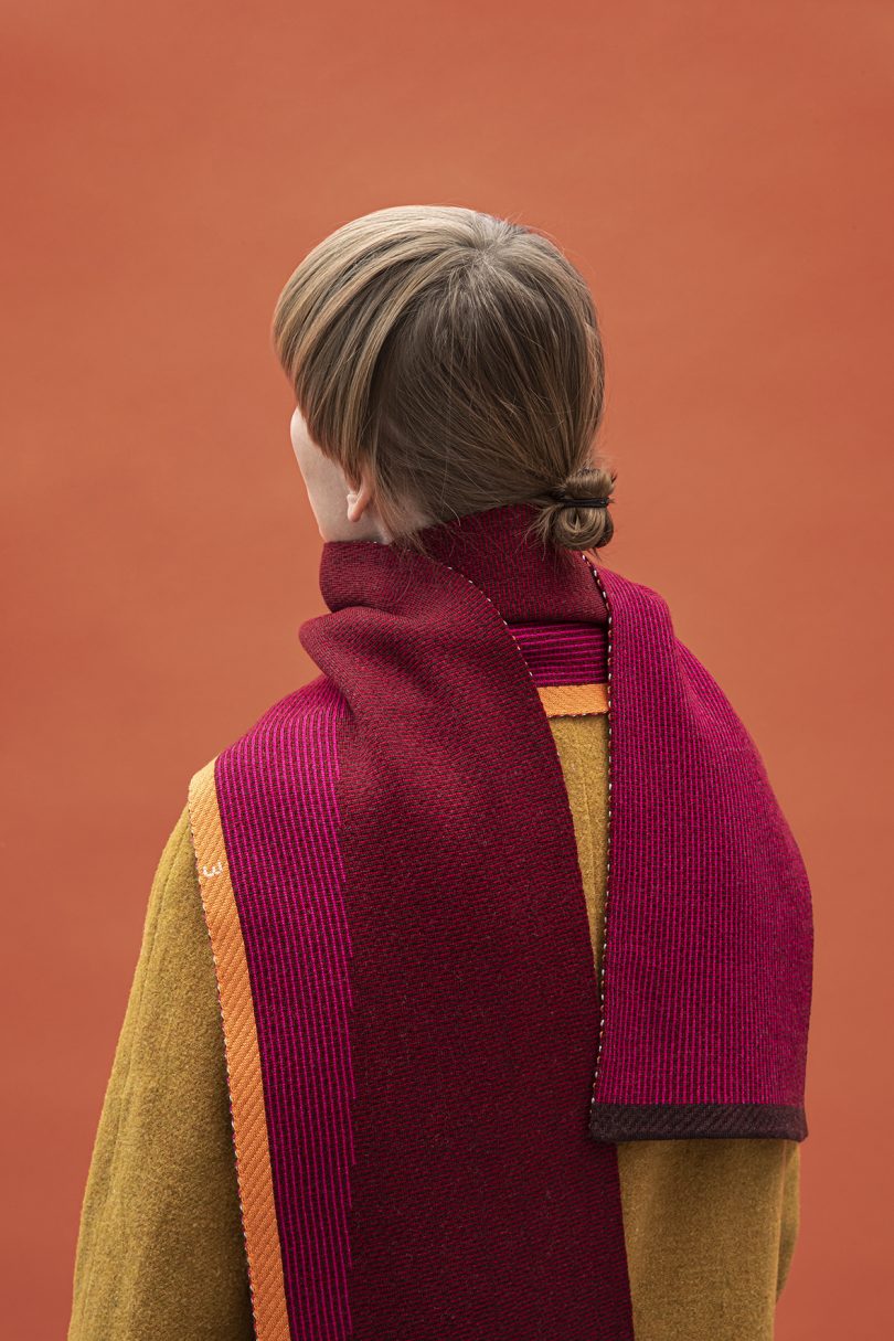 back of person wearing magenta scarf in front of orange wall