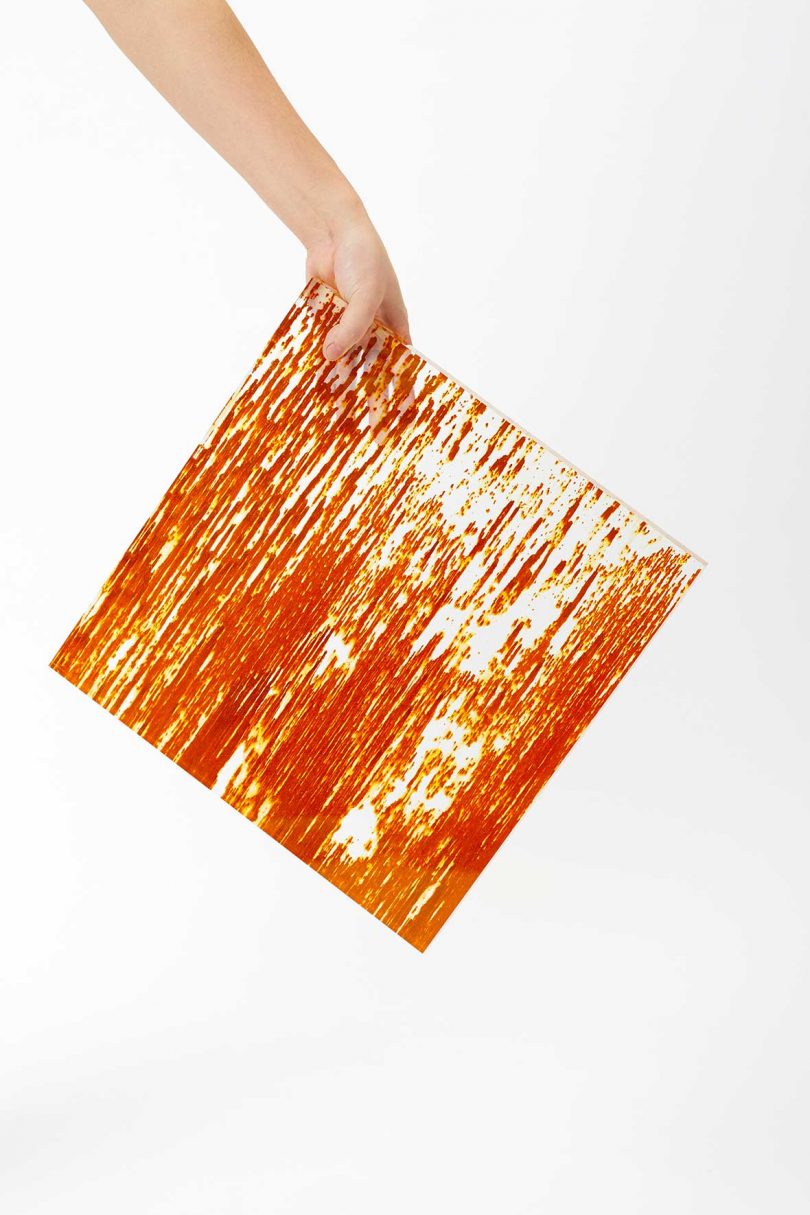 hand hold an orange streaked tile on white background