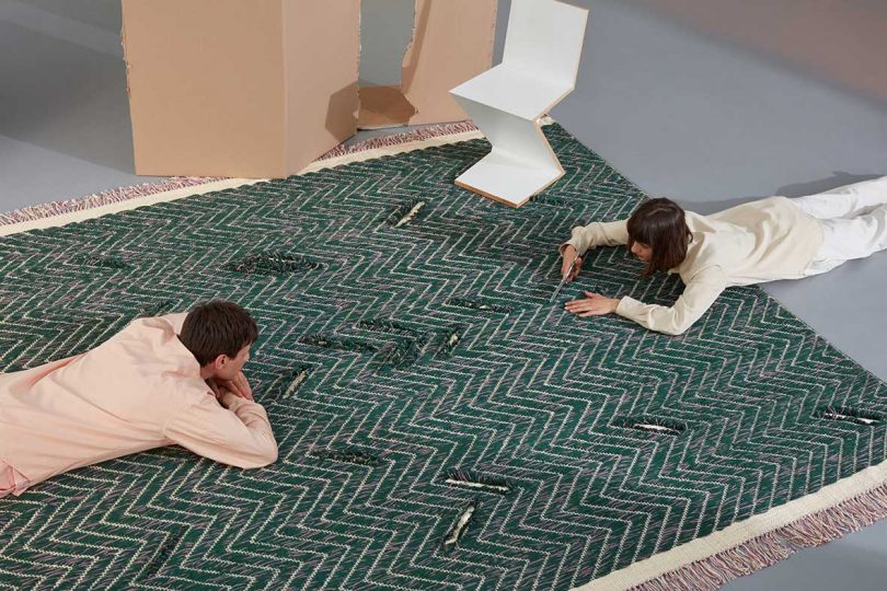 two people laying on dark patterned floor rug