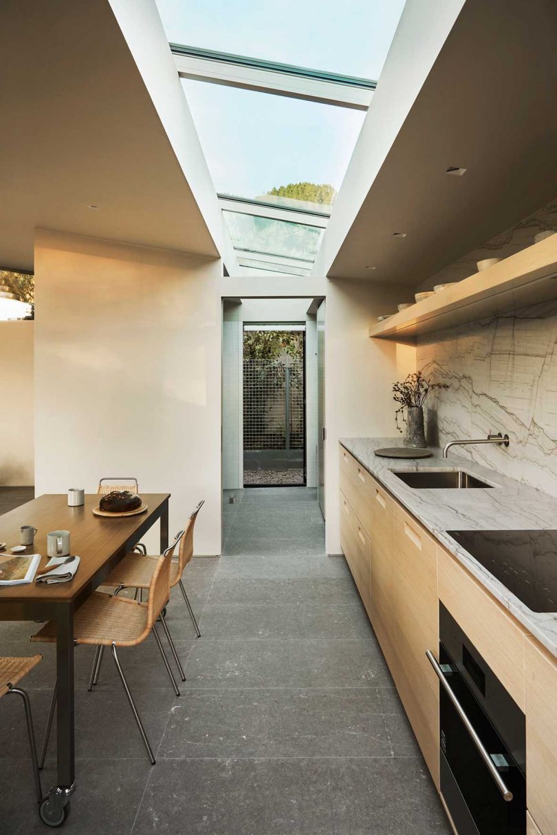 long view of minimalist kitchen with row of skylights overhead