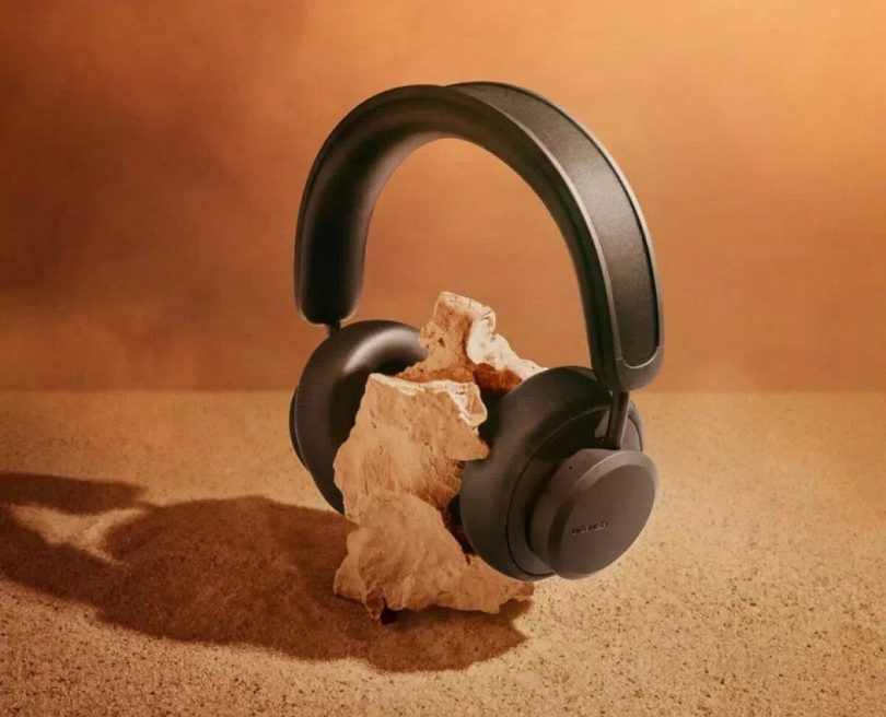 Black headphones set onto a rock with a sandy background.