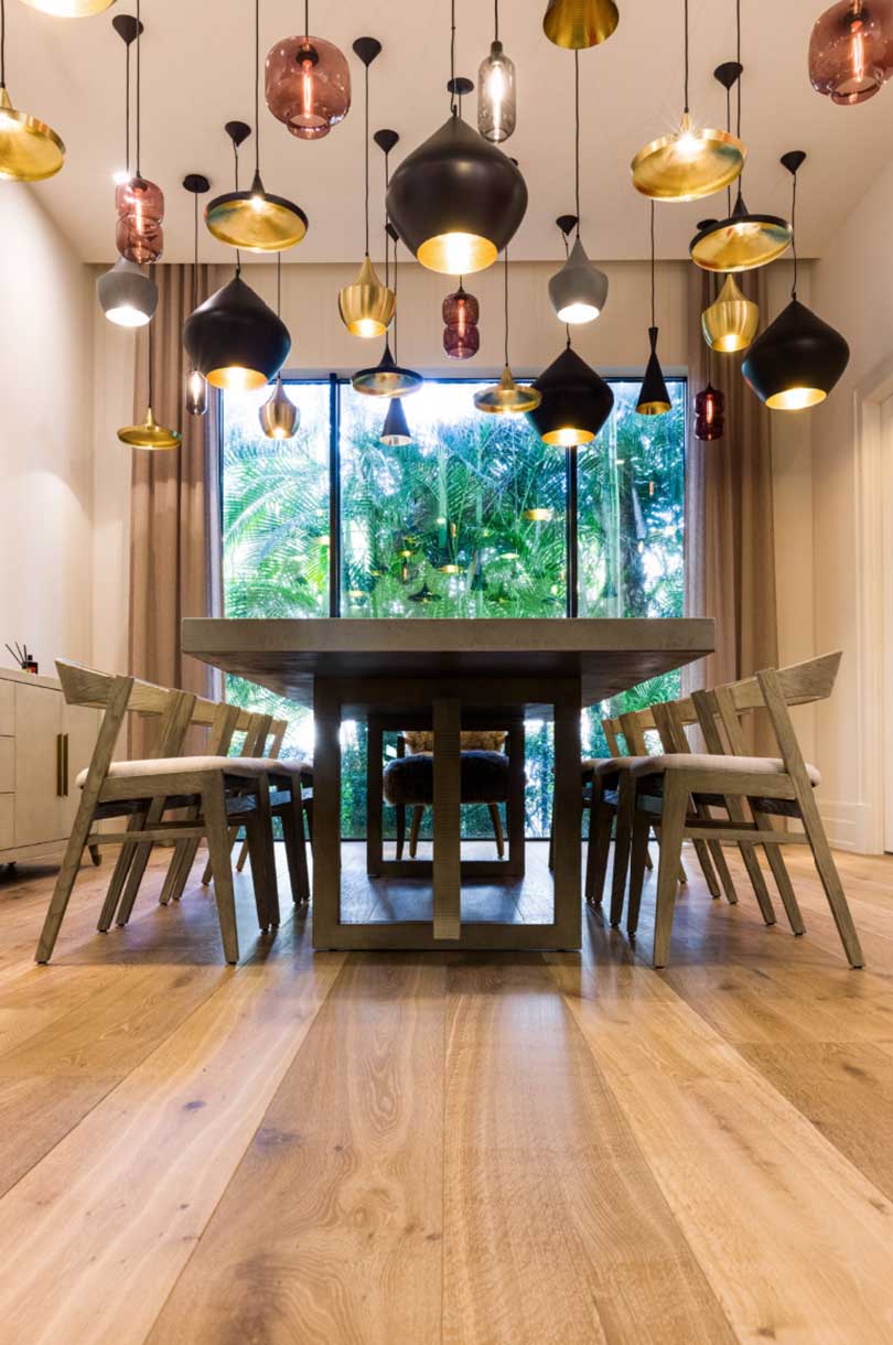low shot of modern dining room with wood table and chairs and a large group of metallic pendants