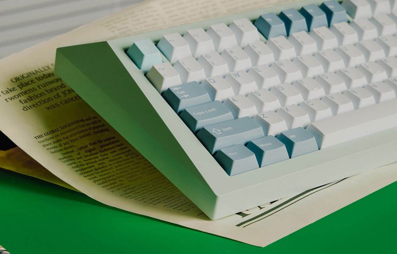 Aquatic green keyboard sitting on top of newspaper.