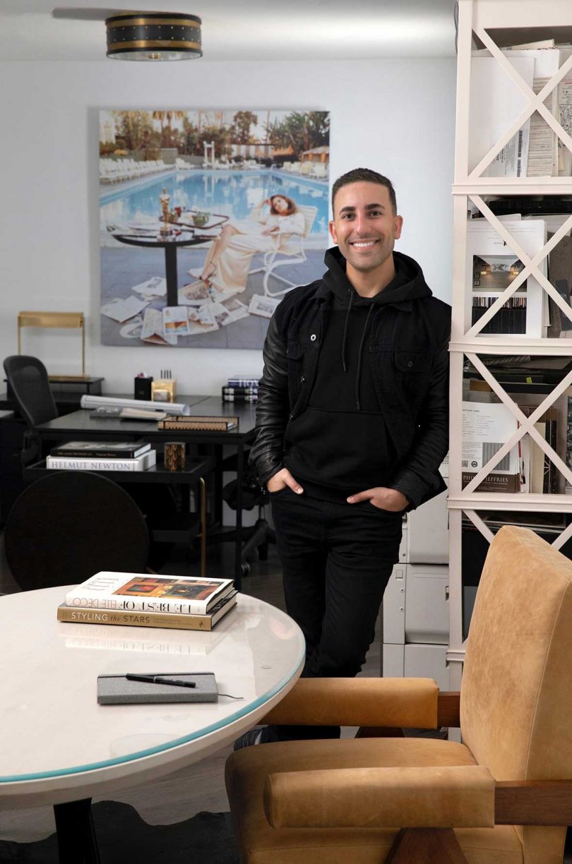 designer ryan saghian standing in office behind white desk with desks and artwork behind