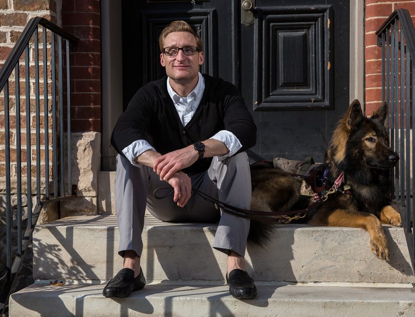 veteran and olympic athlete bradley snyder with his dog sitting on a stoop