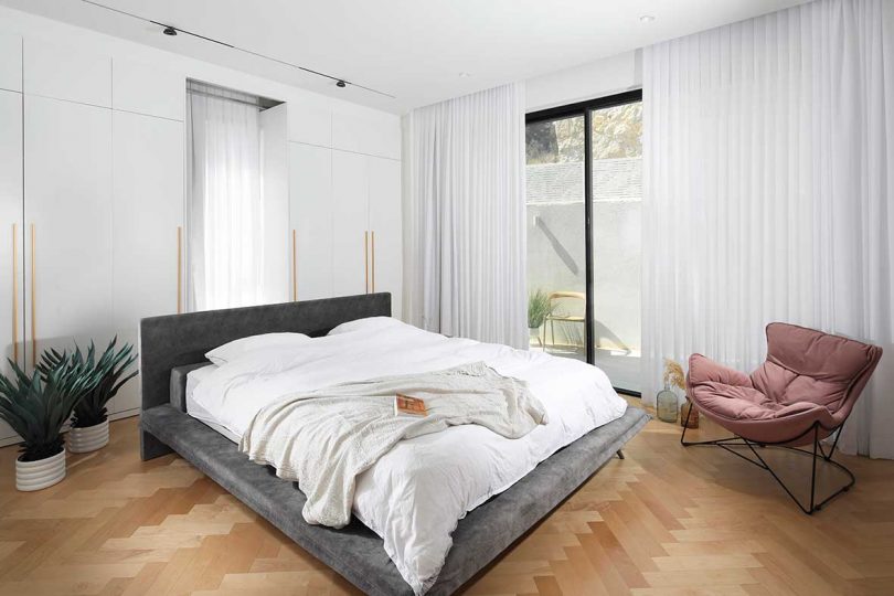 modern white bedroom with gray upholstered bed and white bedding