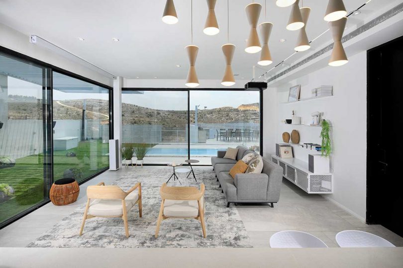 modern white living room with gray sofa and views to pool