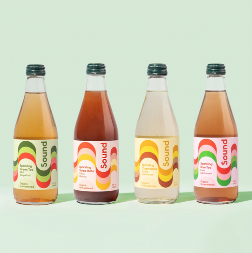 four colorful side by side beverage bottles on light green background