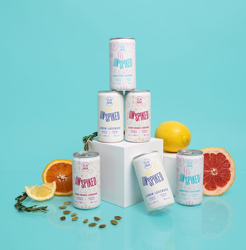 six stacked white beverage cans with citrus fruit on light blue background