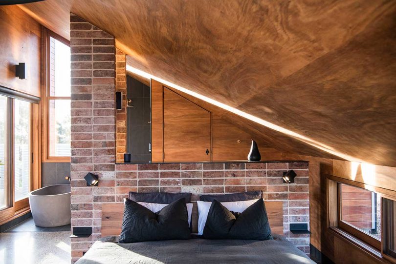 interior of modern hut with bed under slanted wood ceiling