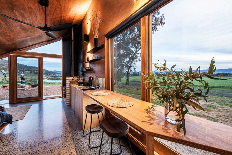 long view of cabin with long countertop that leads to kitchen with outdoor views