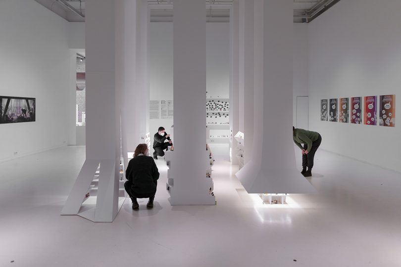 visitors inside interactive exhibition with all white surfaces and small figurines representing people