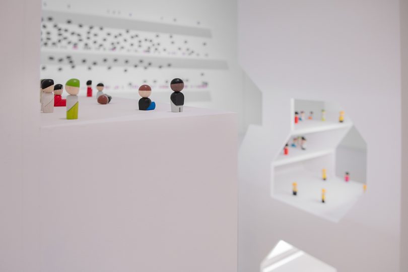 inside interactive exhibition with all white surfaces and small figurines representing people