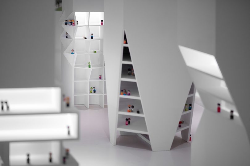 inside interactive exhibition with all white surfaces and small figurines representing people