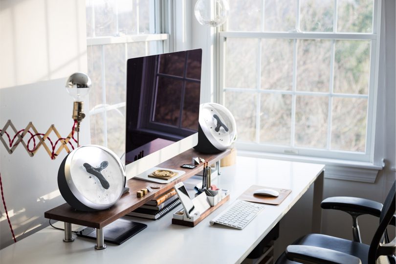 Two Van der Waals speakers set on each side of a desk, alongside an Apple iMac computer.