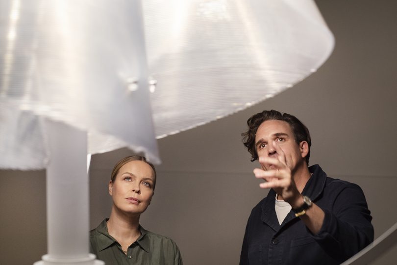 Artist Thijs Biersteker pointing toward detail of sculpture with woman standing beside him.