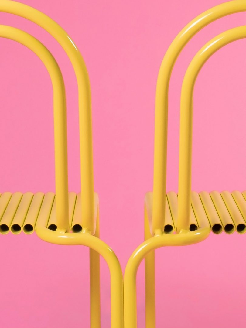 detail of two yellow outdoor dining chairs on bubblegum pink background