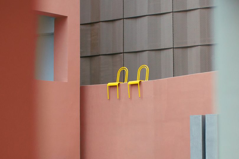 two yellow outdoor dining chairs balanced on top of coral wall