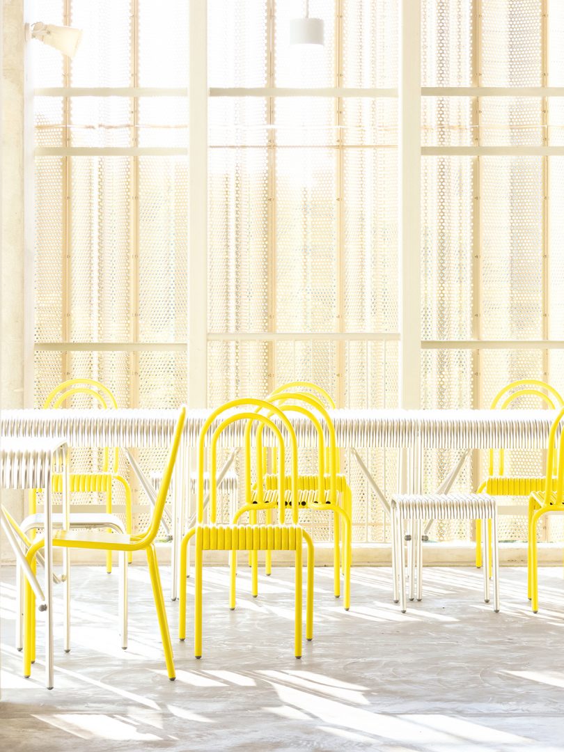 yellow outdoor dining chairs with white table and large windows
