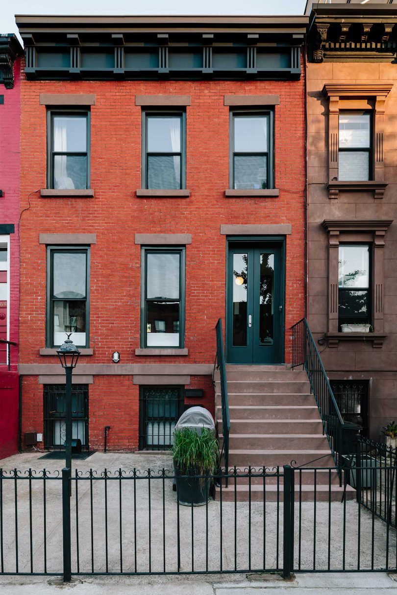 front exterior view of brooklyn townhouse with red brick exterior and black fence