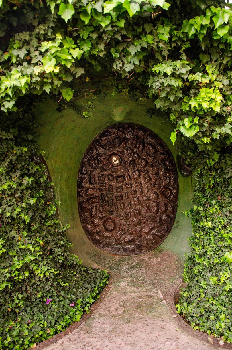 underground house with oval wood door surrounded by greenery