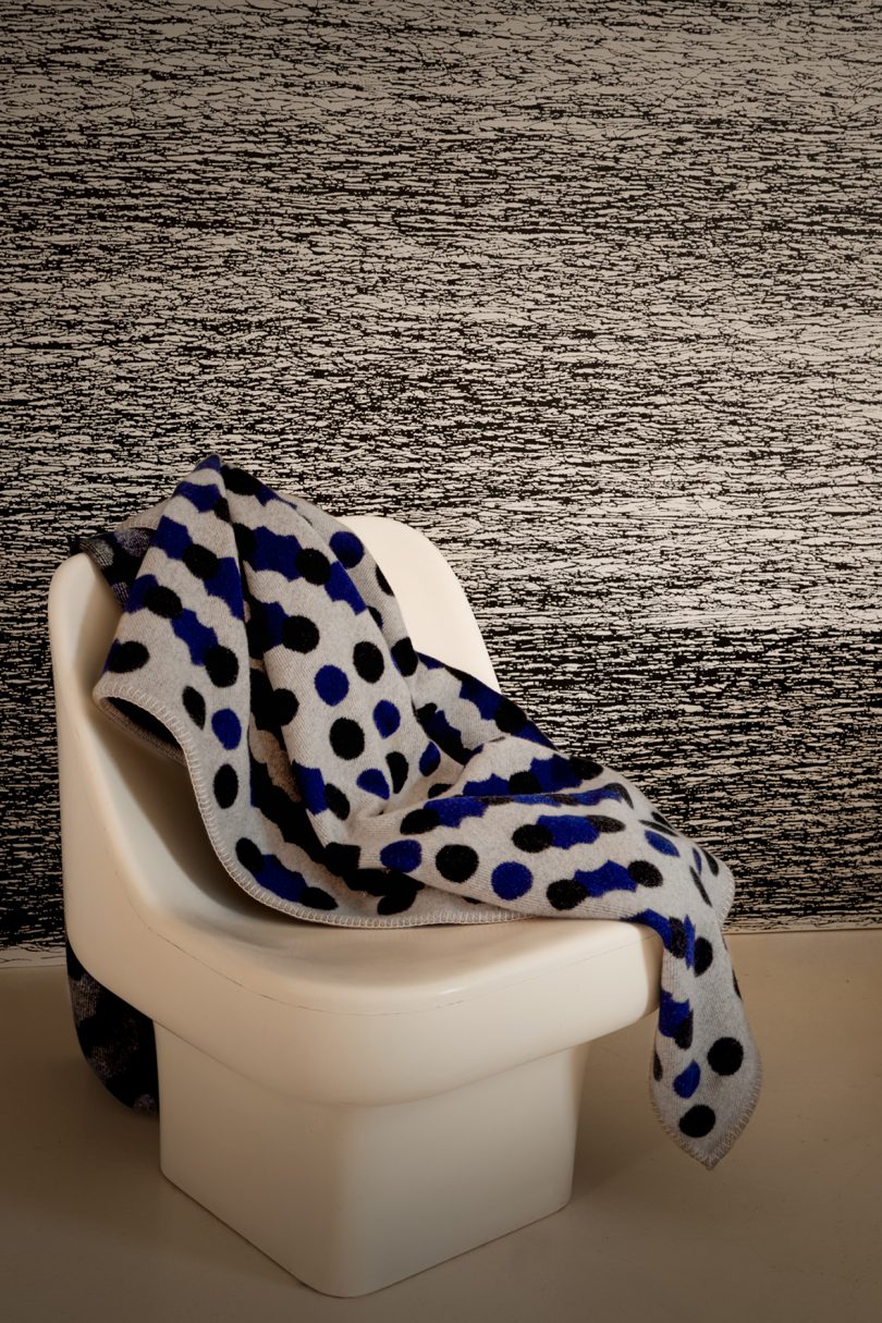 abstract wallpaper behind chair with throw blanket