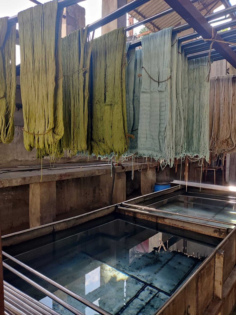 dyed yarn hanging above pools of liquid dye