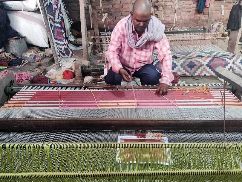 Person weaving a rug