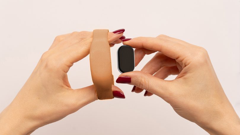 Woman's hands holding Dip silicone wristband on left and sensor unit on the right.