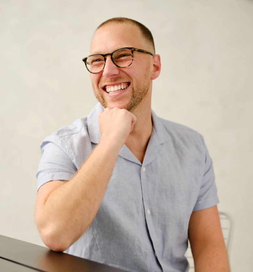 light-skinned man wearing glasses and a short sleeved button up shirt