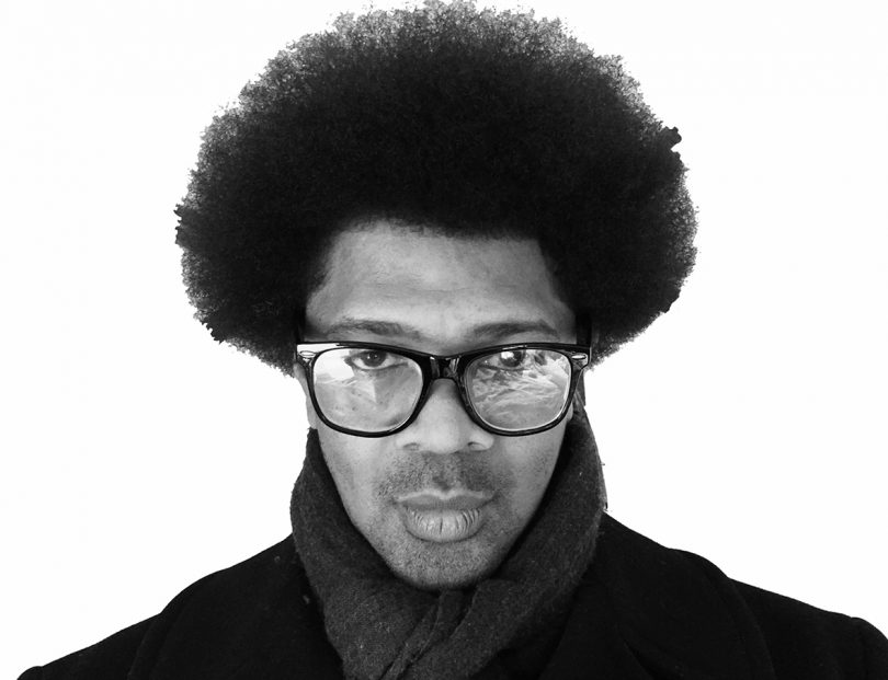 black and white portrait of dark-skinned man with afro and glasses