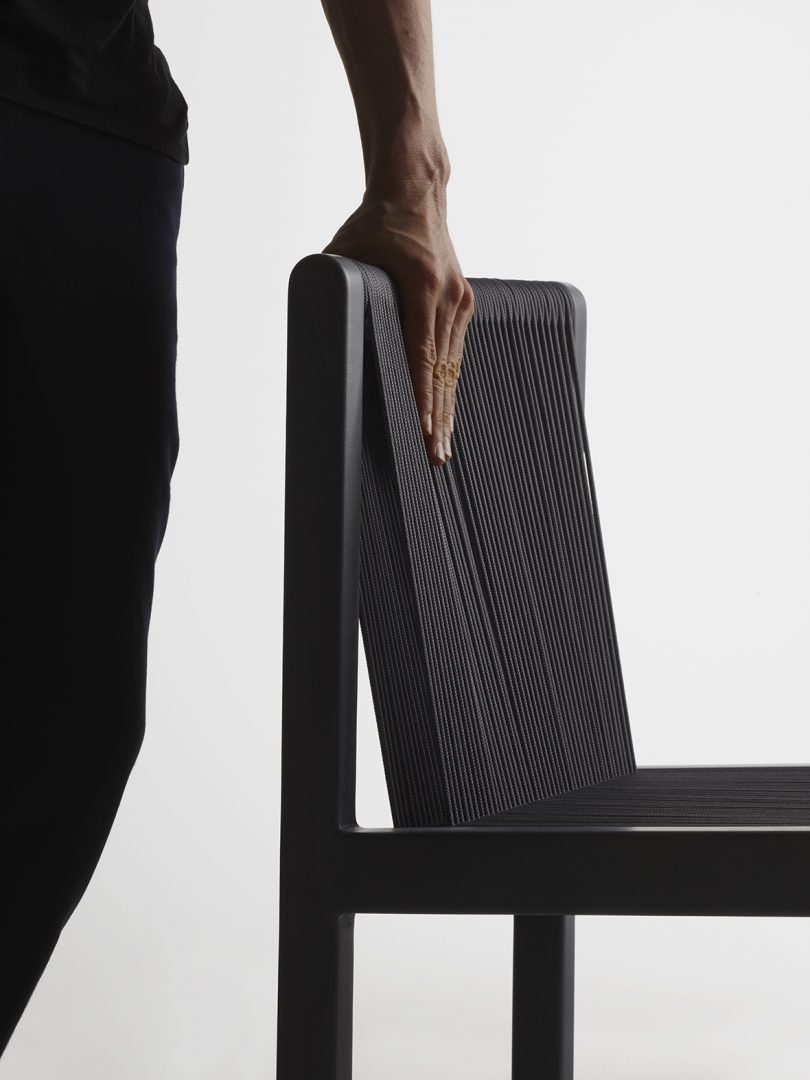 dark-skinned hand leaning on the back of black chair
