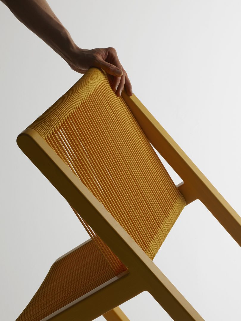 dark-skinned hand tilting yellow chair