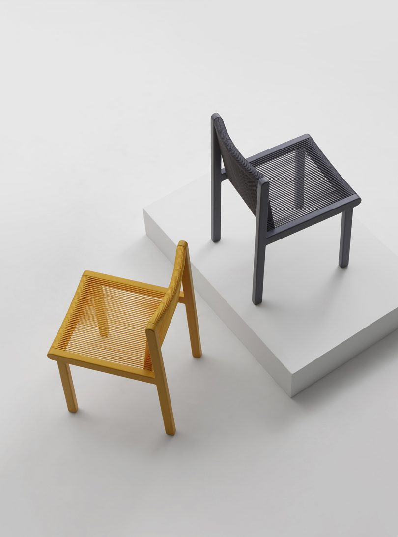 one yellow chair and one black chair on a white platform
