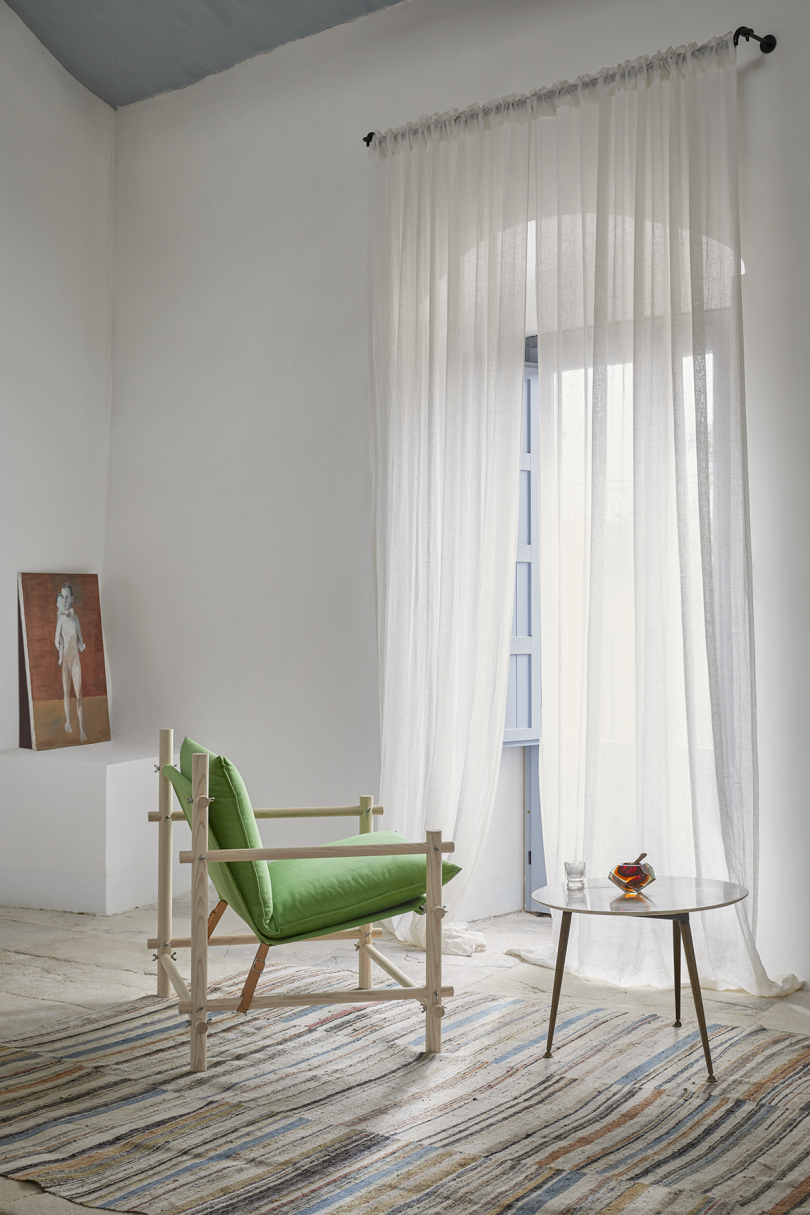 interior space with green chair in front of large window with sheer curtains