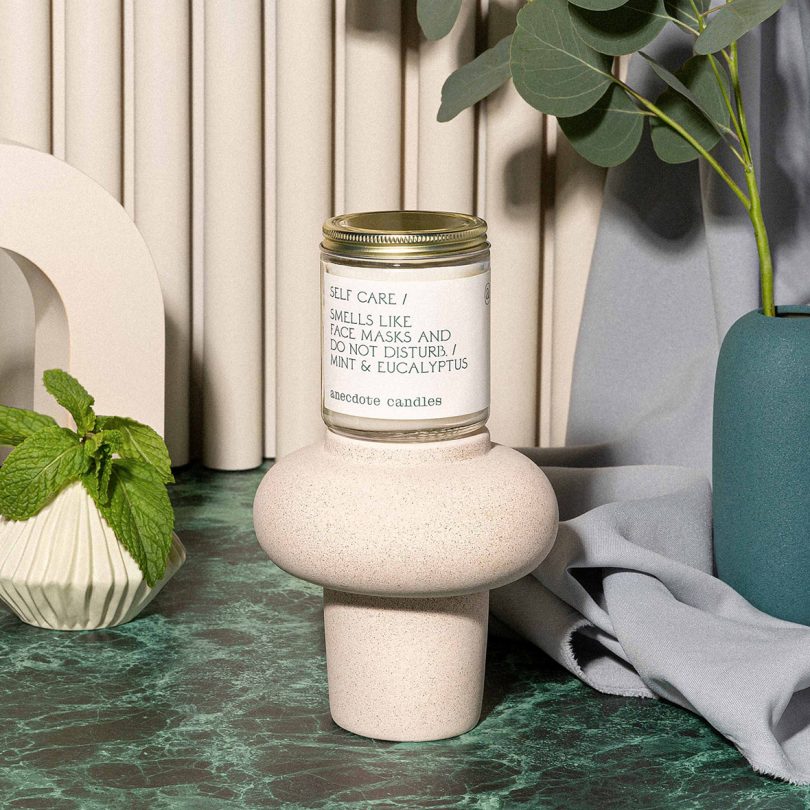 jar candle styled with white vessels and greenery