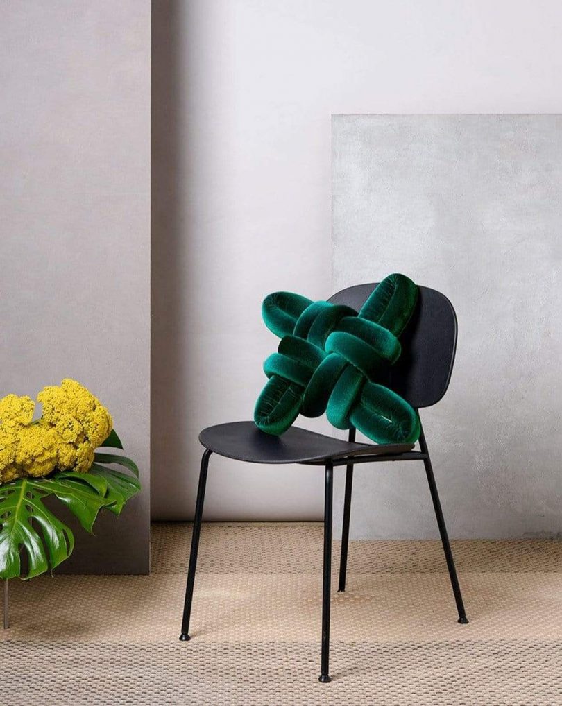 green velvet knot pillow on black chair