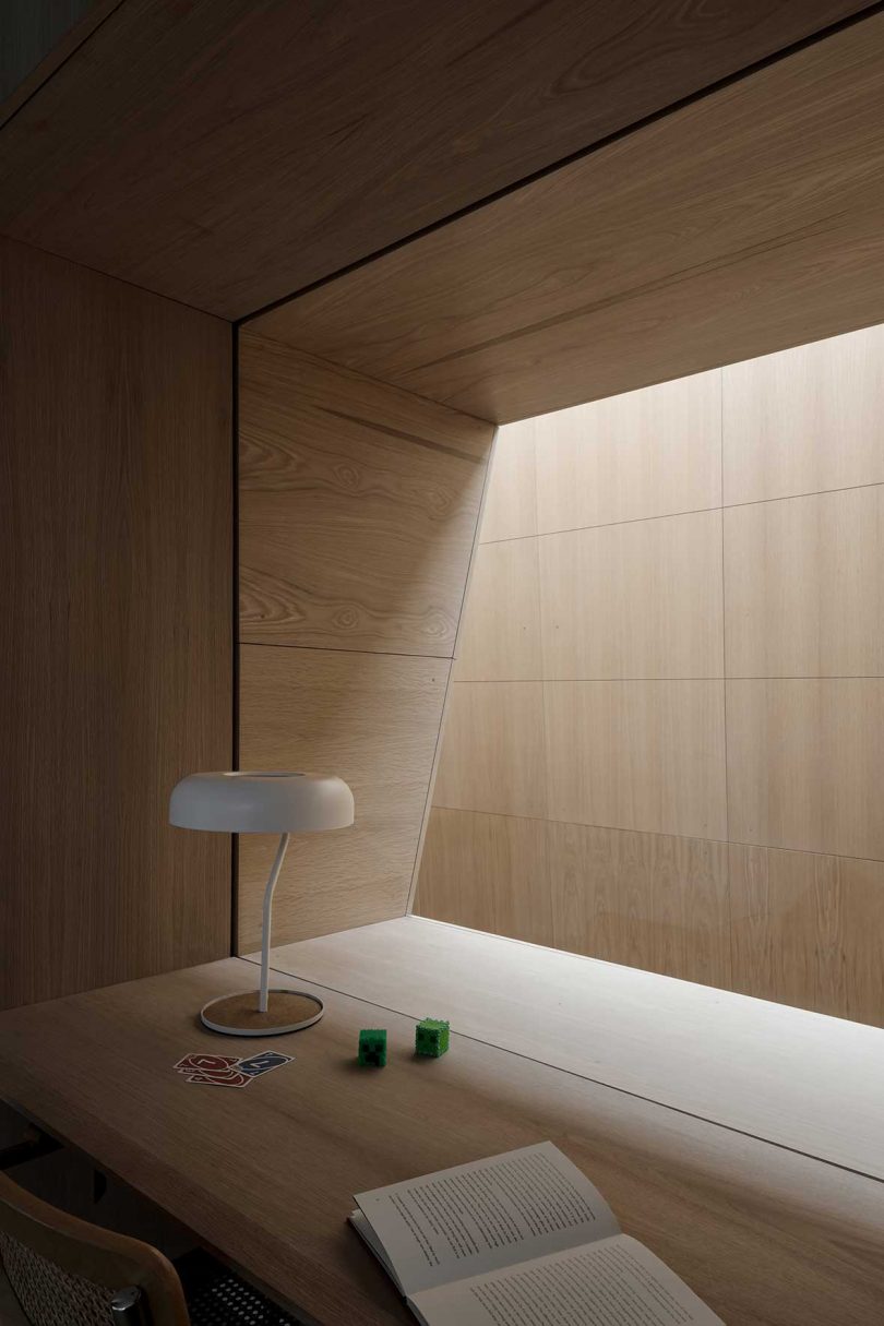modern desk looking through an interior window to a lightwell clad in wood