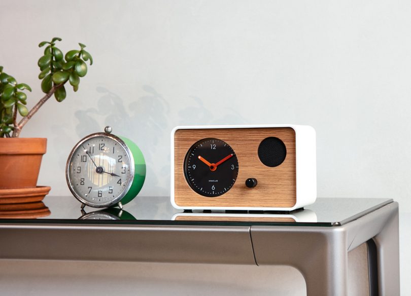 White OneClock next to traditional bell operated circular analog alarm clock