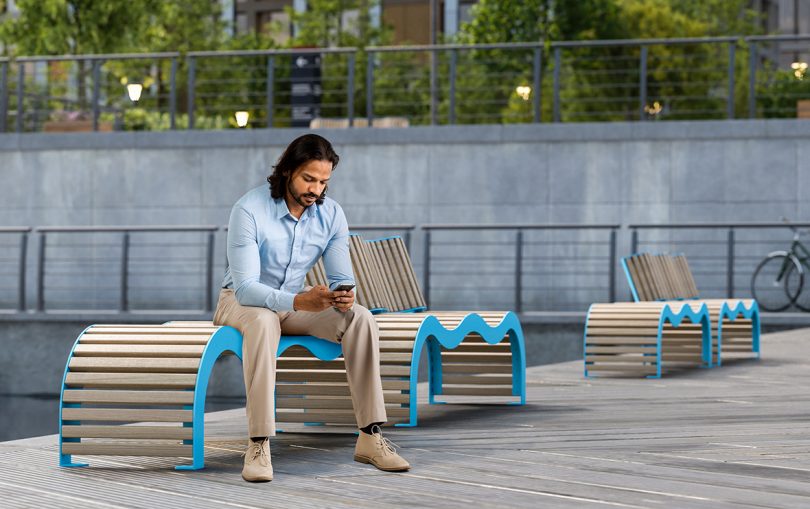 blue and wood benches outdoors with seated man on phone