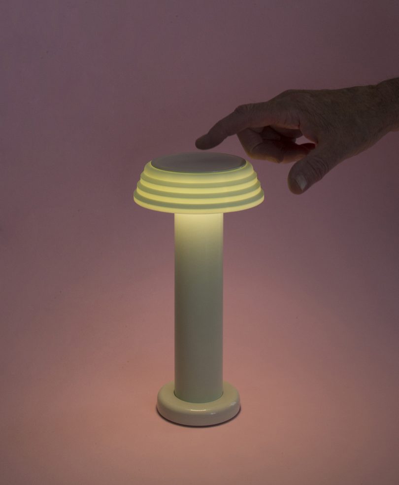hand touching top of lit table lamp