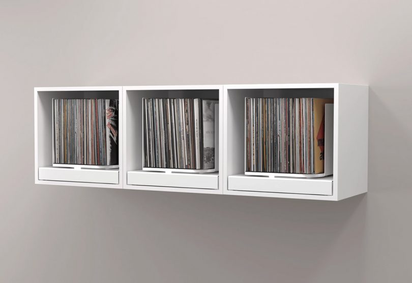 Three white rpm record storage units wall mounted side-by-side as one continual display.